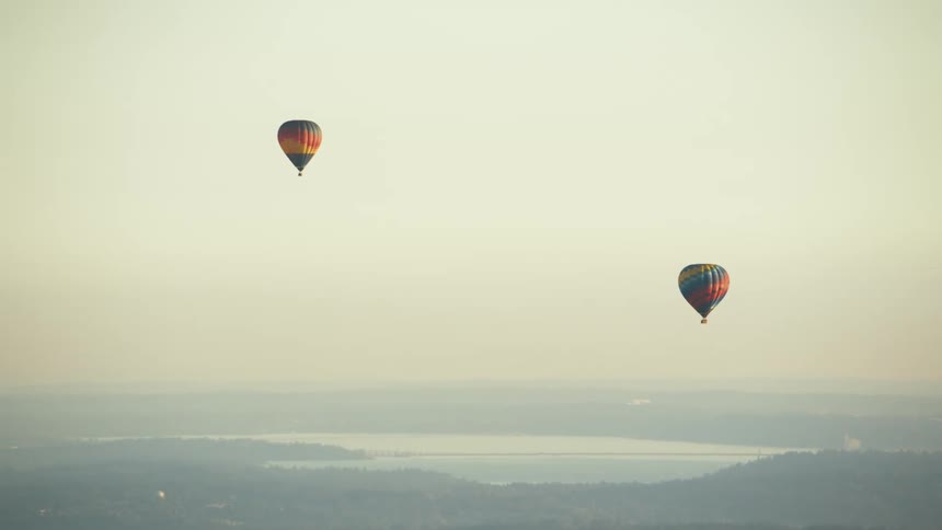 A view of two hot air balloons floating in the air