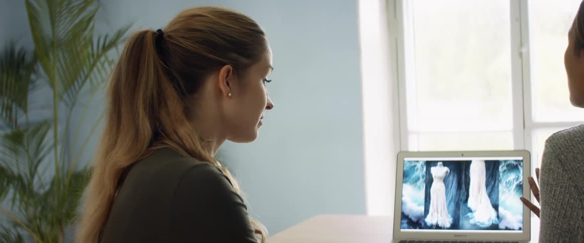 Two women sitting in a room looking at a laptop and talking