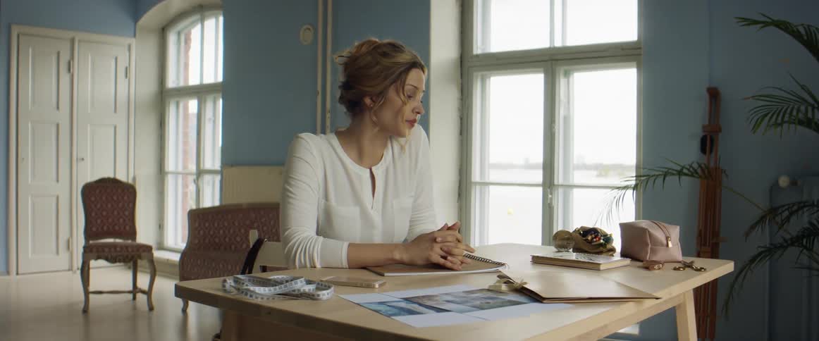 A woman sits at an office table and looks concerned