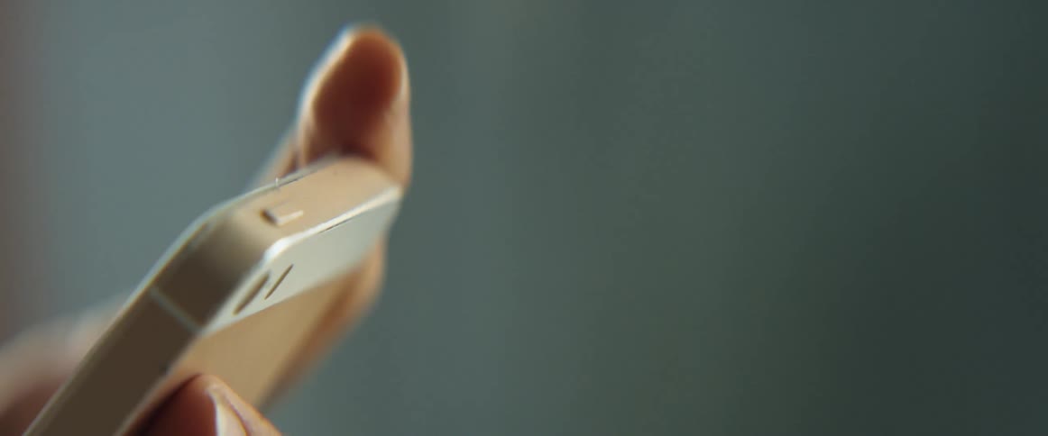 A person holds their smart phone in their hands while using their fingers to operate it