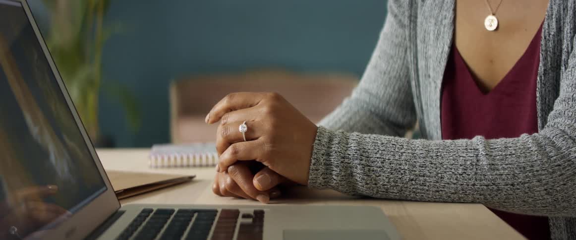 A woman sits at a table beside a laptop