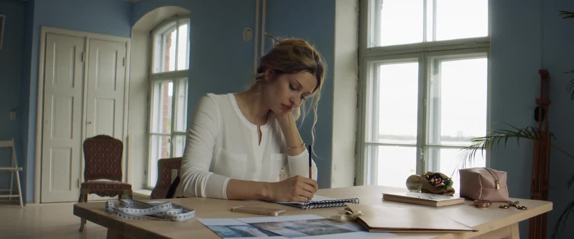 A woman is working on a sketch as she pauses to think