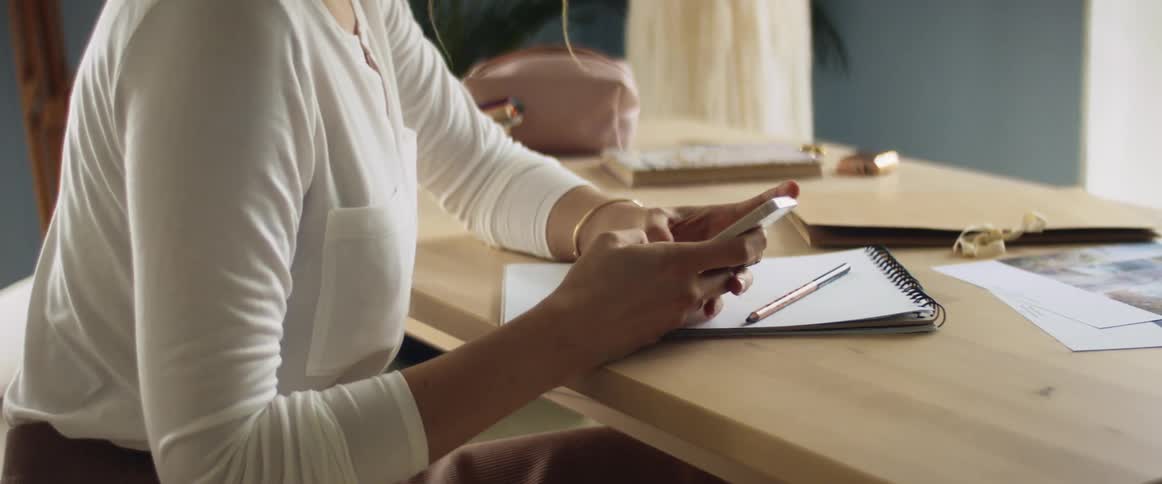 Woman texting on her smartphone while sitting at the desk in her office