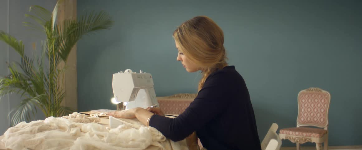 A woman is using a sewing machine to make clothing