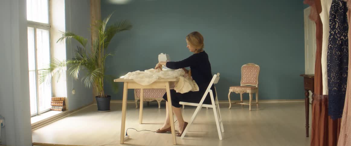 A woman is making a dress on a sewing machine