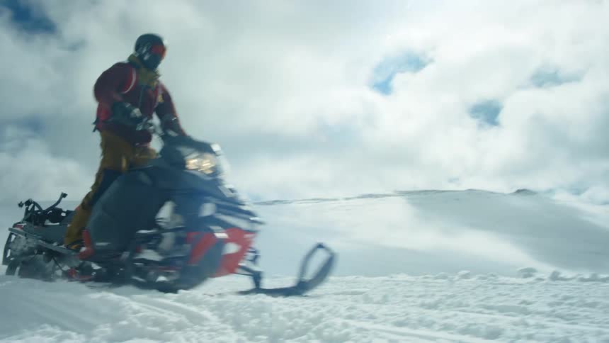 Man driving a snowmobile over the snow covered plains near the mountain