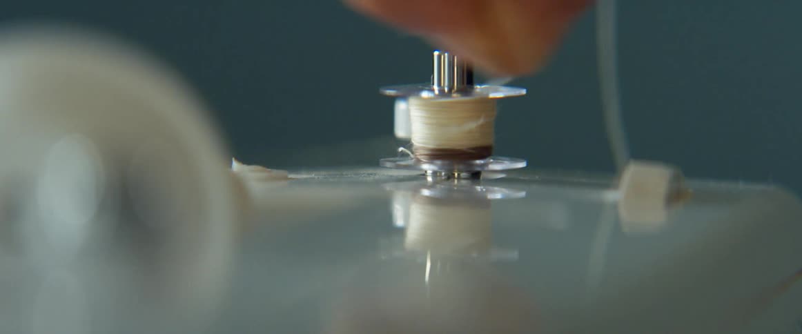 A person in a room twirling a string on a roll on a sewing machine