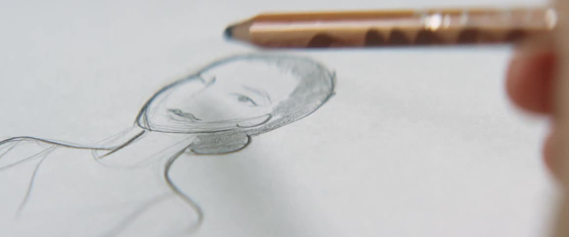 Fingers holding a pencil sketch and shade a drawing of a woman