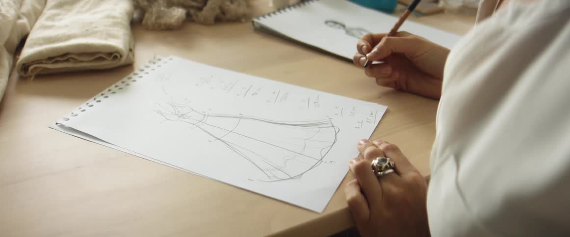 Young blonde fashion designer drawing a design on paper on her studio