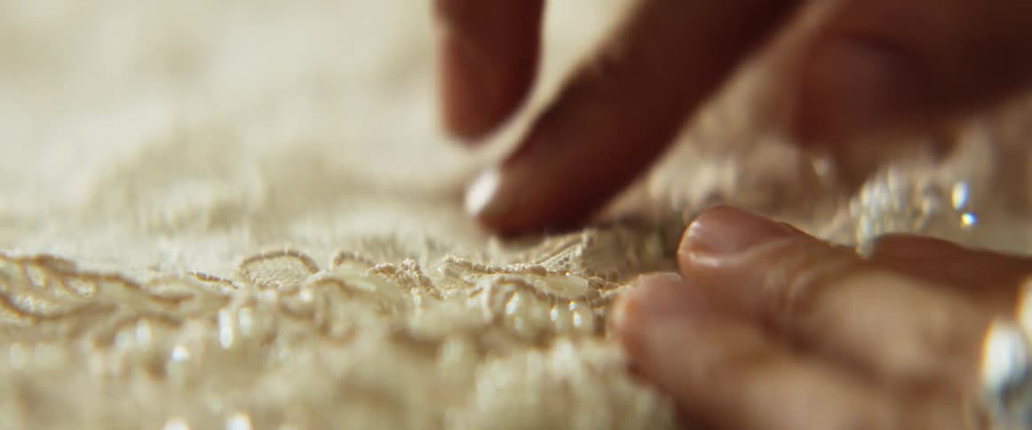 A close up of a womans hand placing lace