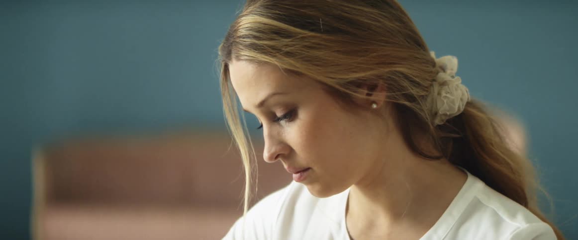 Woman looks down as she works in room with sofa set against blue wall