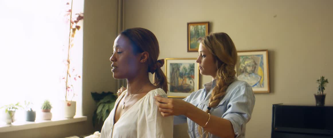 A woman uses a measuring table to measure the shoulders of another woman indoors during the day