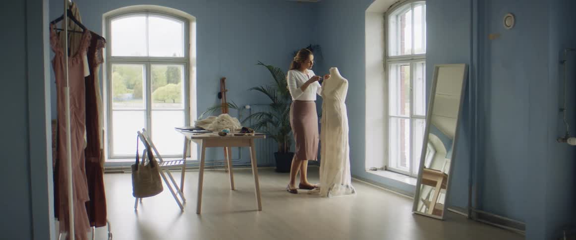 A seamstress sews a dress on a manequin
