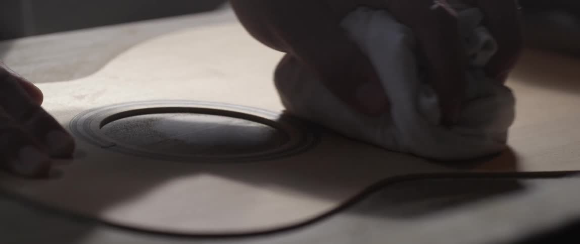 A person smoothes a wooden surface with a cloth