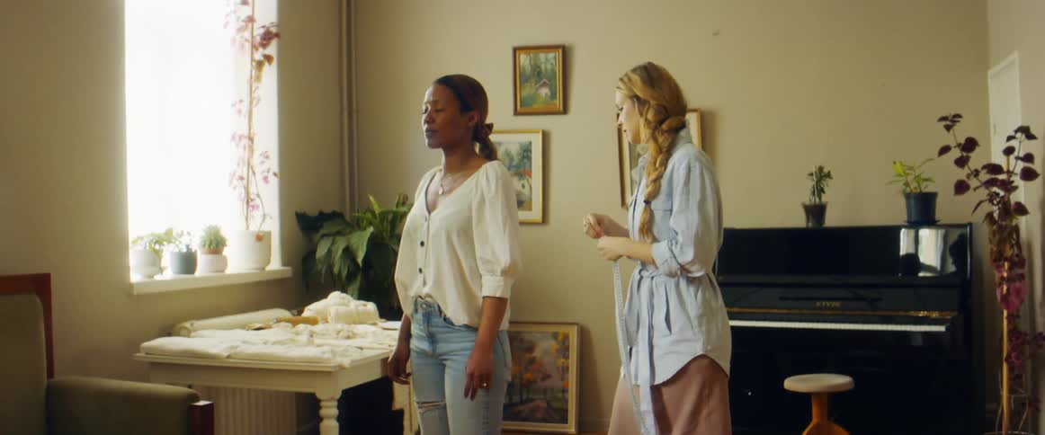 A woman measuring another woman with a measuring tape