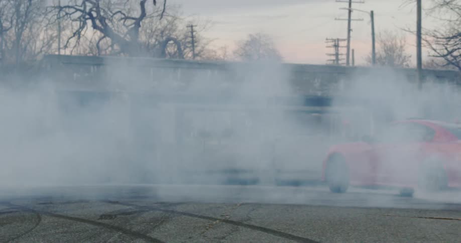 A red sports car spins and swerves around before driving off down a road