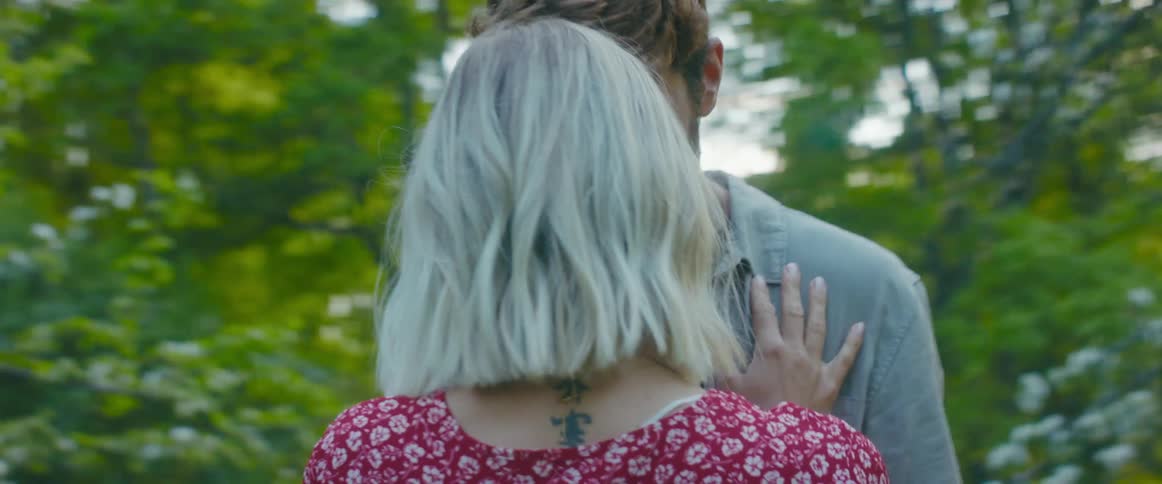 A man and woman stand close together outside then hug and kiss
