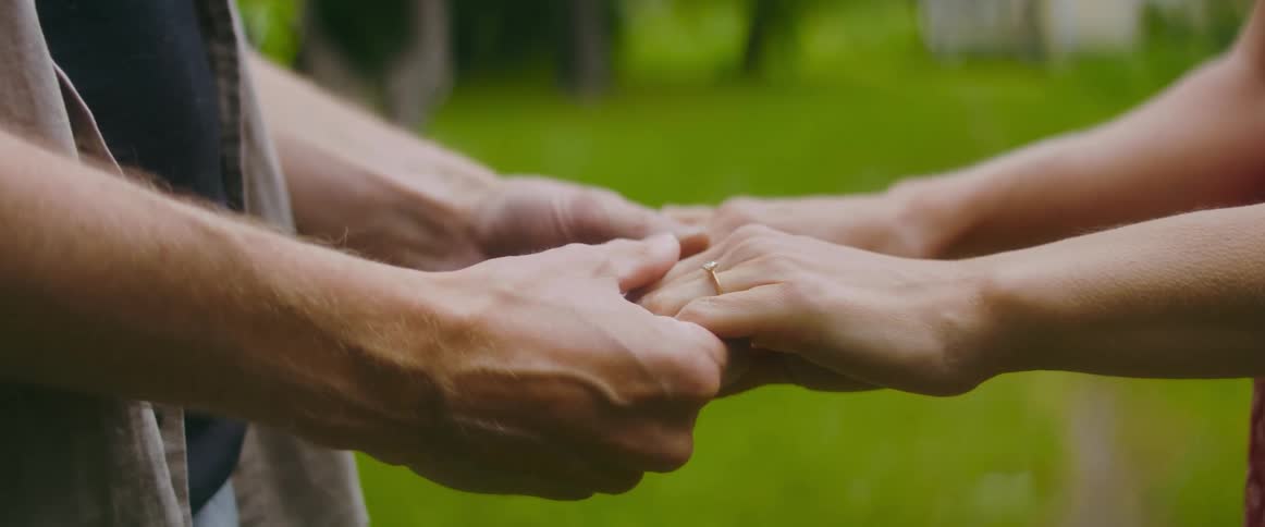 Young couple standing over green grass holding hands