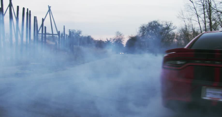 A car drifting and doing donuts with trees the sky and clouds in the background