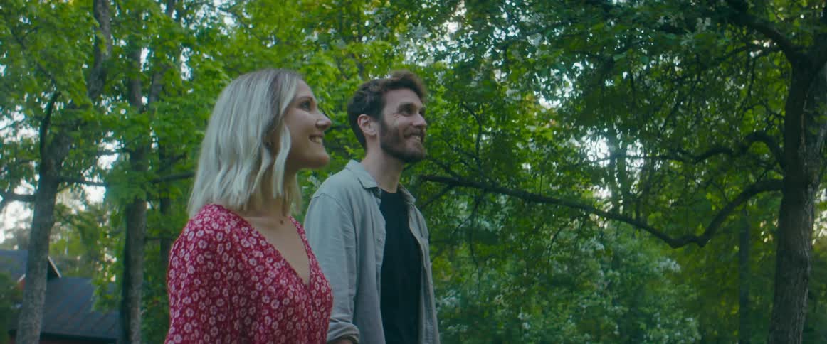 A couple look up at the neighborhood trees as they walk and talk