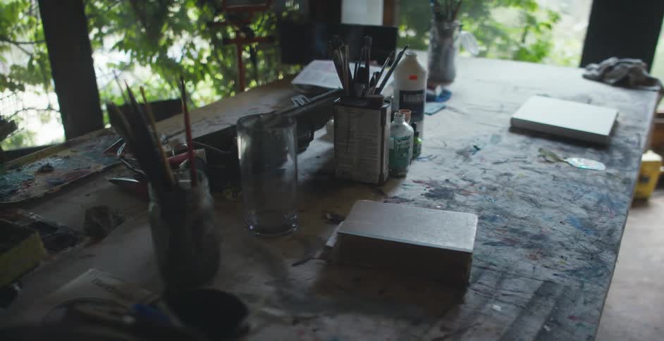 A room with a table with books jars and paint brushes