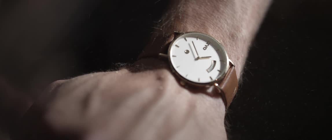 Saw dust flies over a persons hand wearing a watch