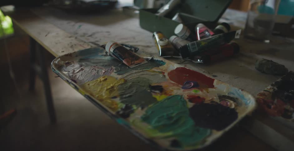 Painters pallet filled with colorful oil inks place over a wooden table