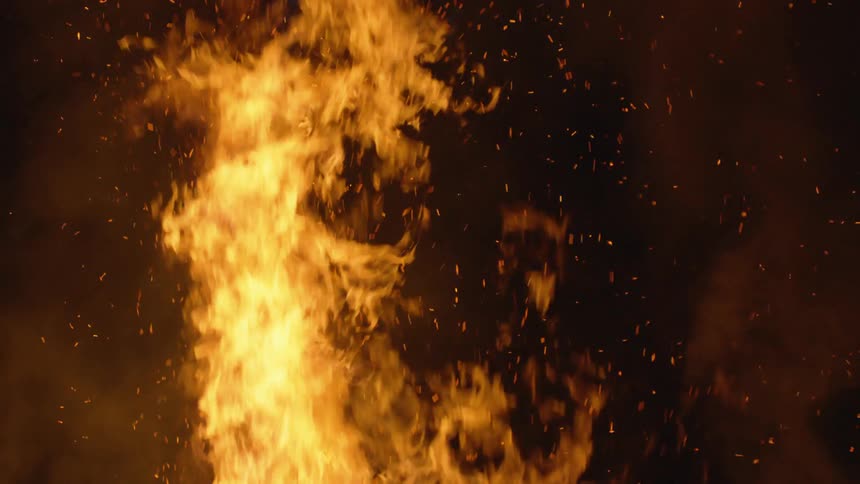 A fire is burning with flames and sparks in a dark sky