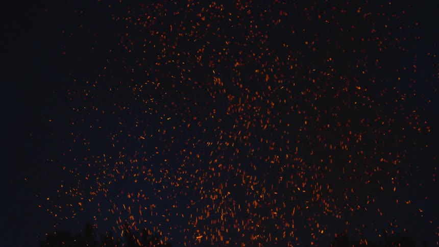 In the darkness there are countless small embers drifting upwards from a fire below