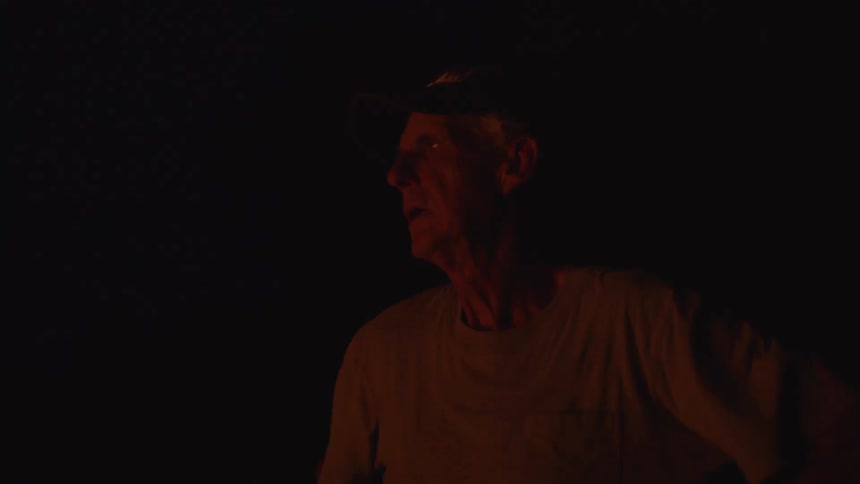 A man standing near a fire camping at night