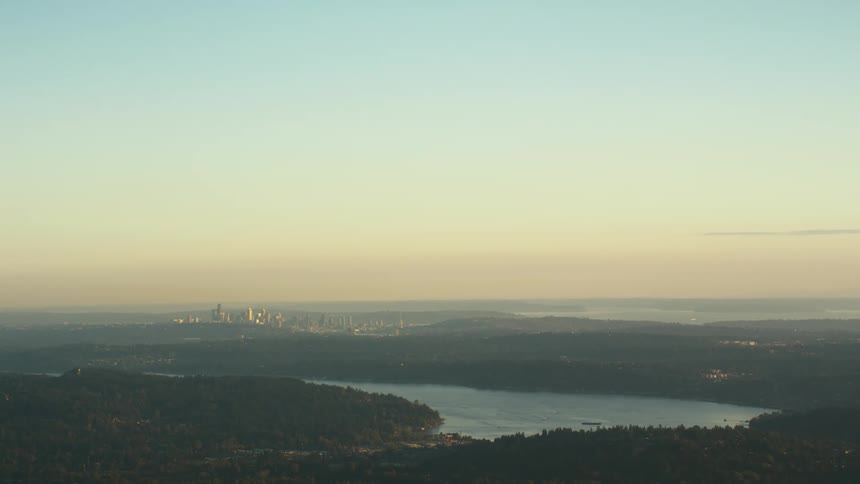 A river surrounded by trees with a city skyline the sky and clouds in the background