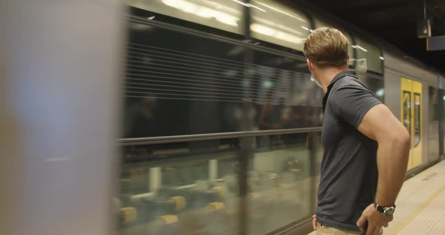 A man looks at his phone standing in a terminal when the subway approaches