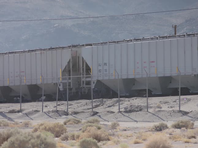 Train cars parked on a track beyond a fence during the day