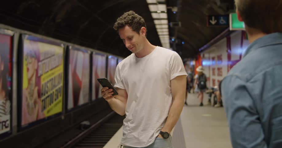 Two men standing with a phone waiting for a subway