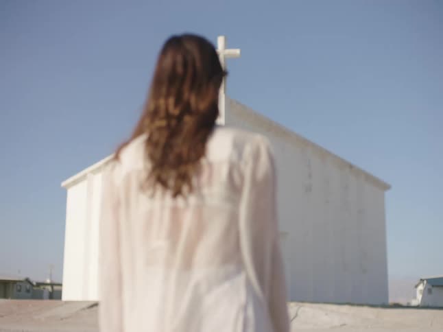 A woman walking towards a church in the desert