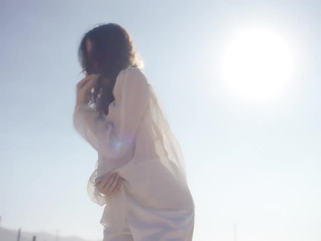 A woman is dancing outdoors in what seems to be a countryside place