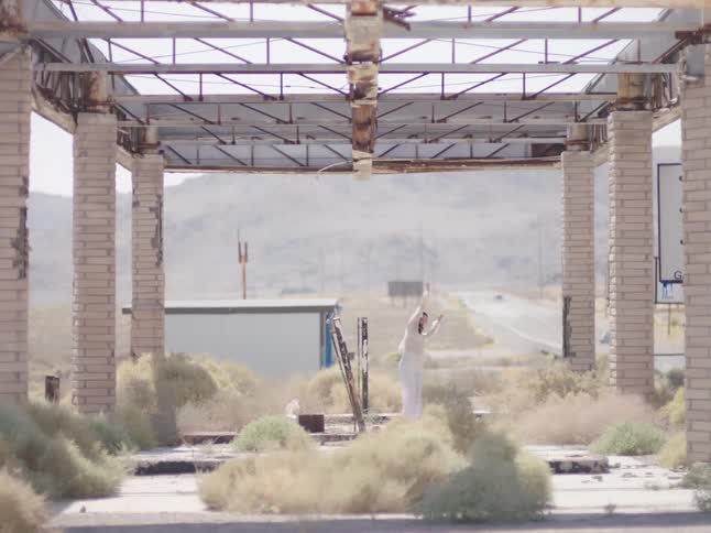 A woman dances in an open air atrium near rolling hills
