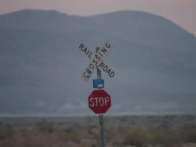 A rail road crossing sign is in the desert