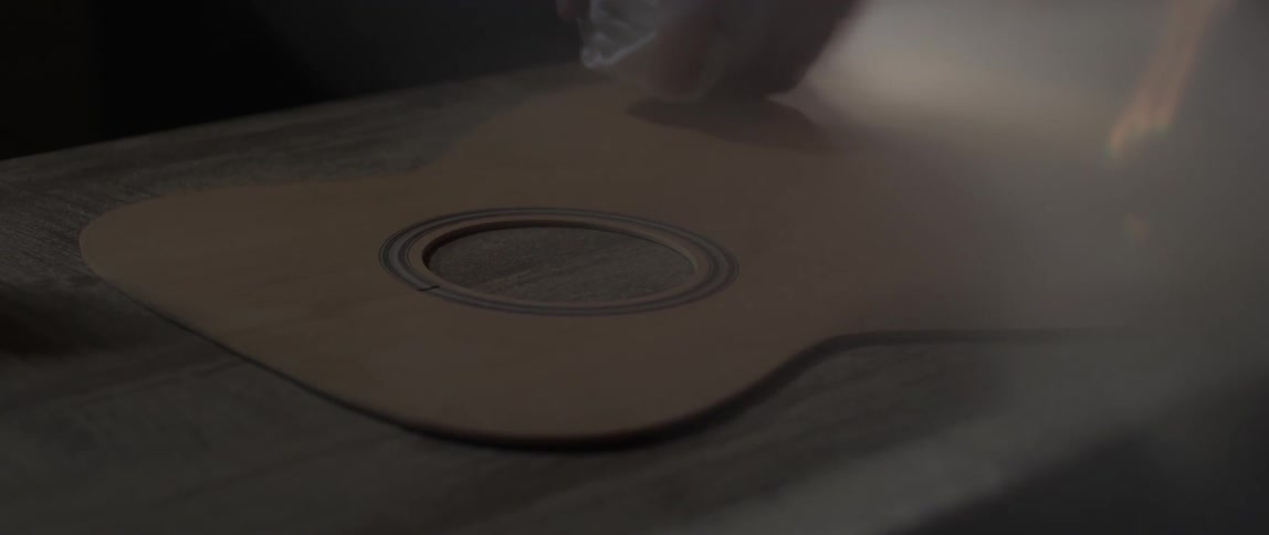 The front wood panel of a guitar is shown in a shop