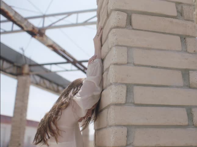 A woman is leaning against the brick wall