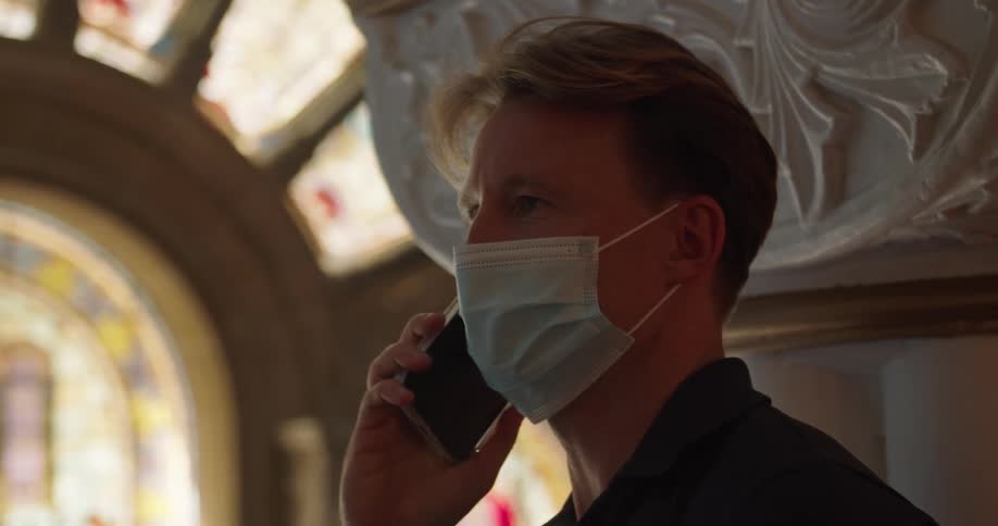 A man answers and talks on a cellphone while wearing a mask