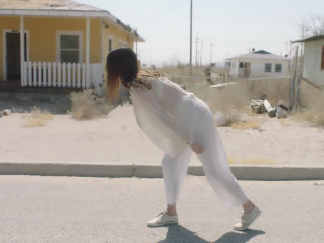 A teenage girls walks through a neighborhood and then starts to dance