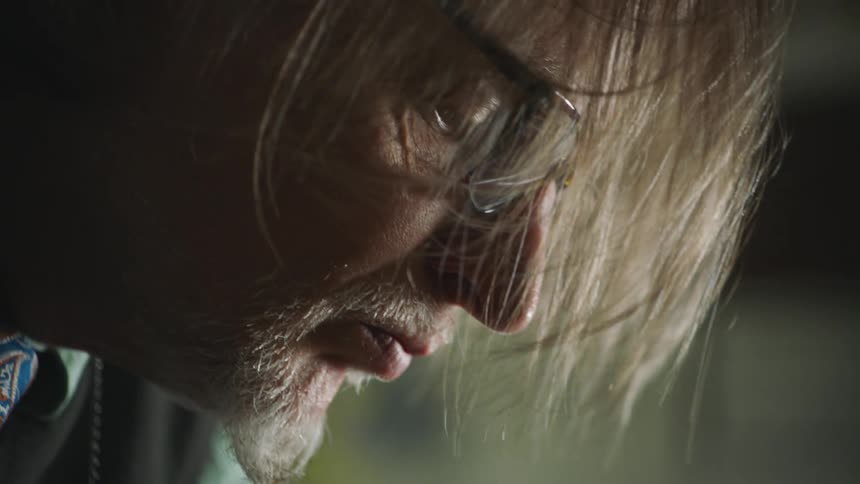 A man with long hair focuses on his work