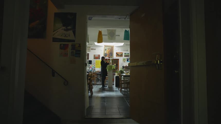 A male art teacher puts flowers in a vase for a still life