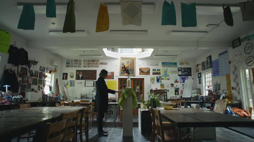 An art teacher arranges flowers for a still life in a classroom