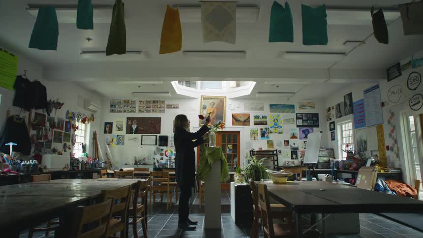 A male art teacher puts flowers in a vase for a still life