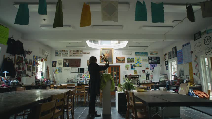 A male art teacher arranges flowers in an art classroom