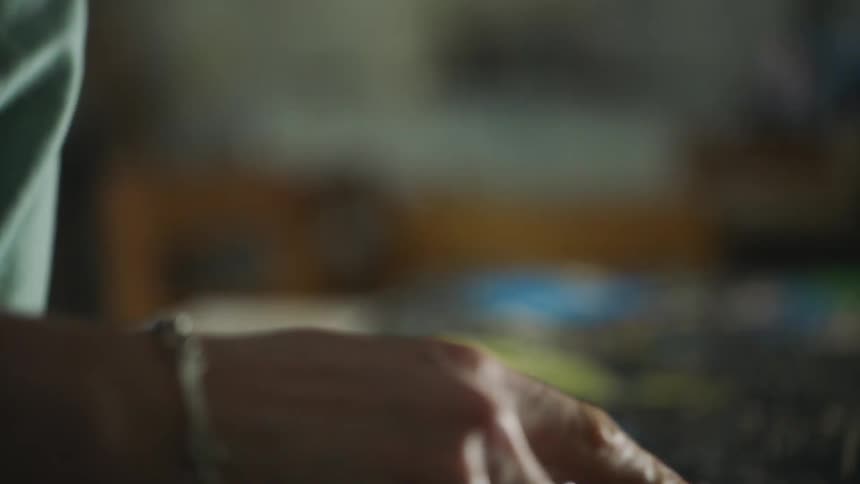 A man with long hair works on an art project