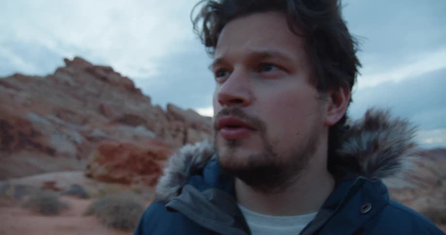 A photographer walks through a desert canyon with a dlsr camera