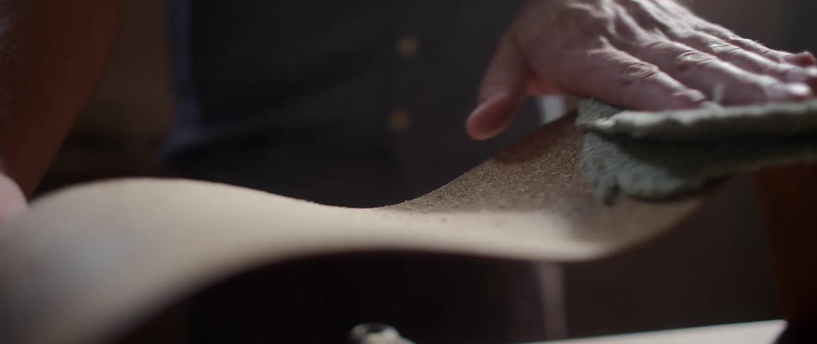 Sawdust is wiped off a piece of curved wood